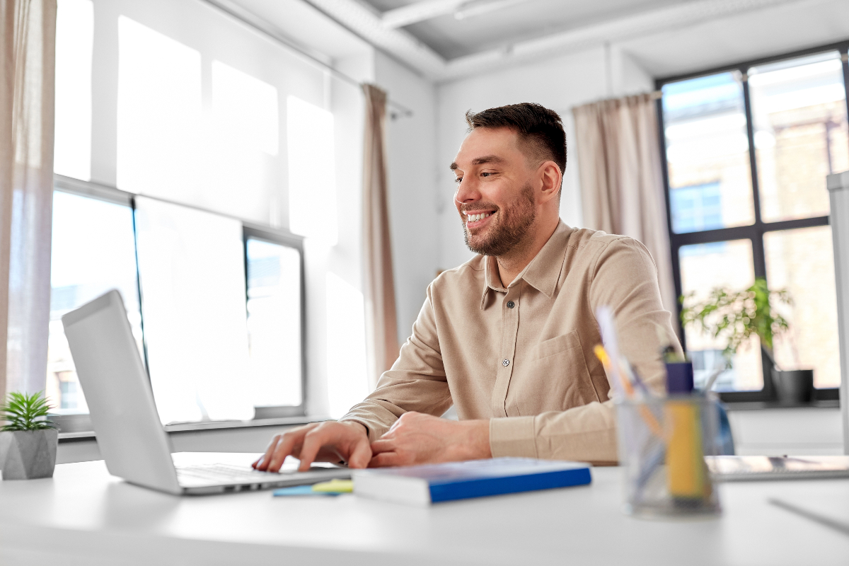 Smiling man looking at laptop screen to illustrate medical coding internships