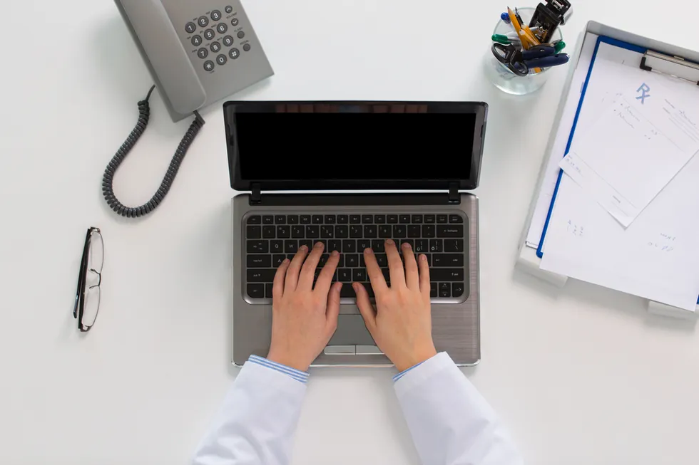 Medical coder working on a laptop beside a clipboard, representing Louisiana medical coding internship experience
