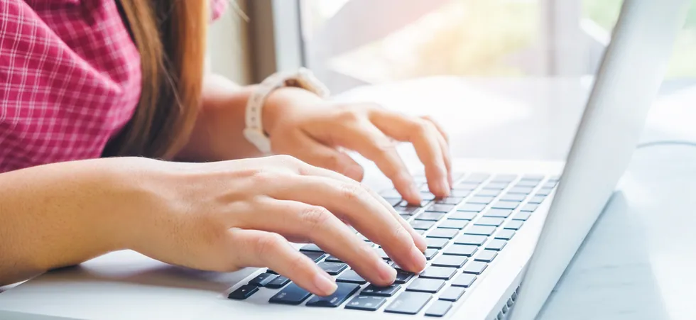 Student typing on a laptop during online medical coding training in Louisiana